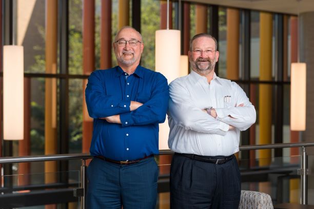 Two men standing next to each other with arms crossed