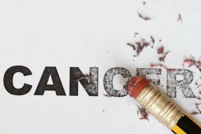 Cancer written on paper and erased by a pencil eraser